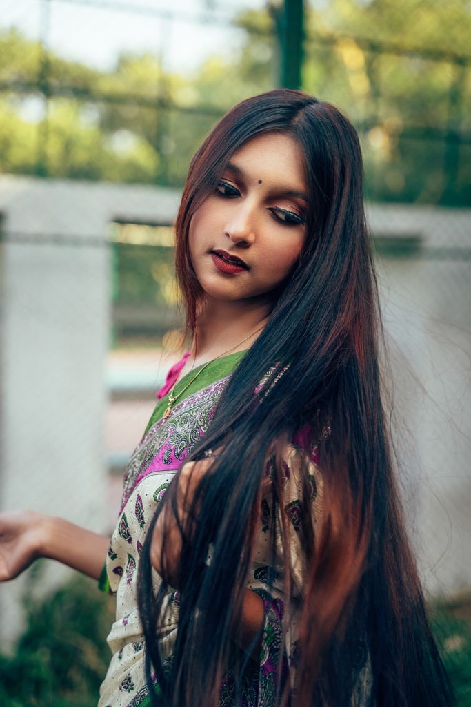 Elegant South Asian woman wearing a traditional saree, captured outdoors with a natural backdrop.